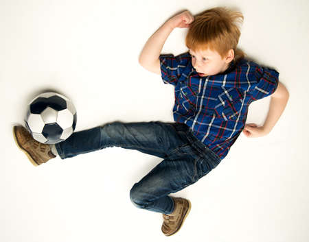 Little funny redhead boy kicking soccer ballの写真素材