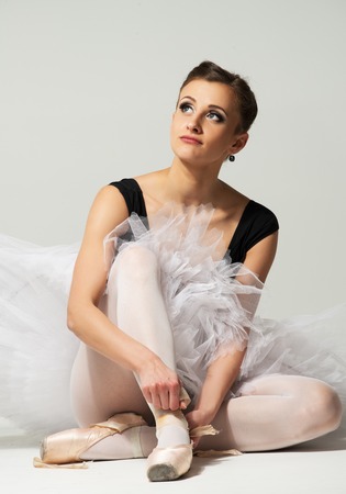Beautiful young ballerina dancer sitting on a floorの写真素材
