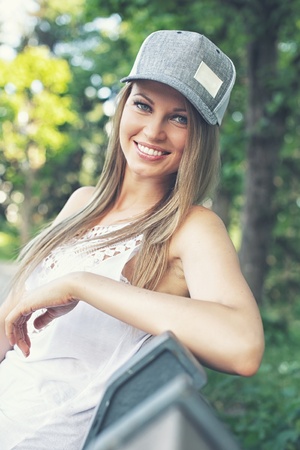 Beautiful young smiling sporty girl sitting on a bench in a parkの写真素材