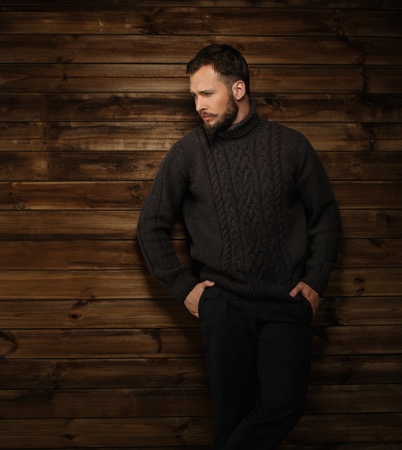 Handsome man wearing cardigan in wooden rural house interior の写真素材