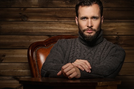 Handsome man wearing cardigan in wooden rural house interior の写真素材