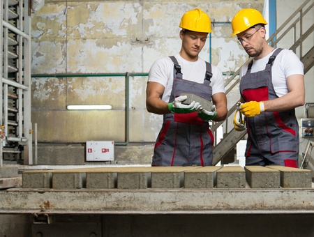 Worker and foreman in a safety hats performing quality check on a factory  