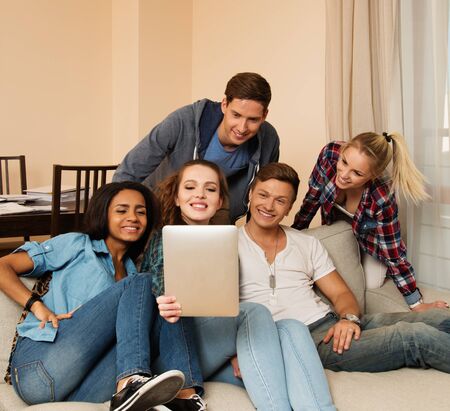 Group of young multi ethnic friends taking selfie in home interior 