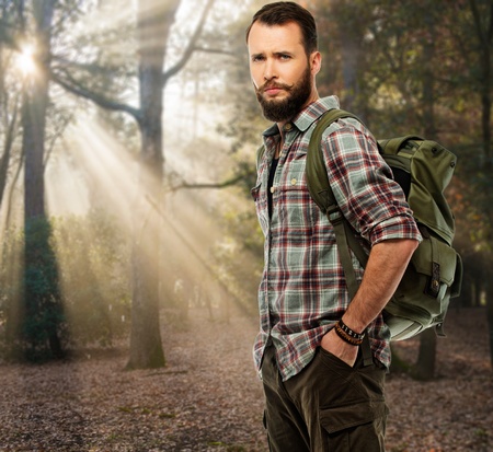 Handsome traveler with backpack in autumnal forest の写真素材