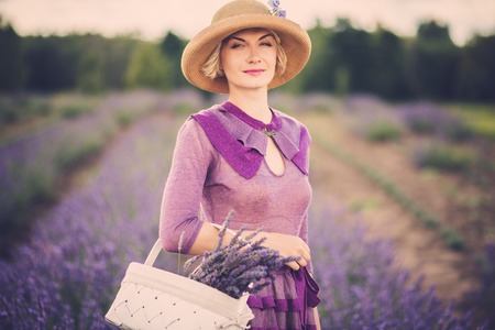 Woman in purple dress and hat with basket in lavender field の写真素材