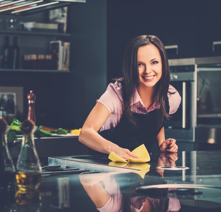 Young cheerful woman cleaning modern kitchenの写真素材
