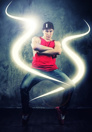Stylish man dancer showing break-dancing moves with magic beams around him の写真素材