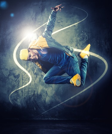Stylish man dancer showing break-dancing moves with magic beams around him の写真素材