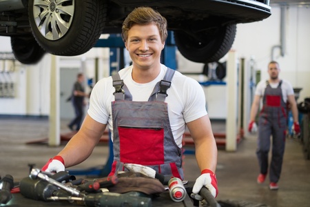 Young mechanic with tools in a car workshopの写真素材