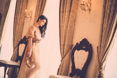 Beautiful young woman near window in luxury house interior の写真素材