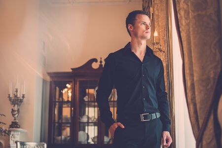 Handsome young well-dressed man in luxury house interior 
