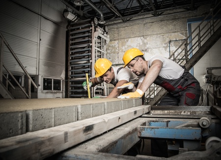 Worker and foreman in a safety hats performing quality check on a factory  