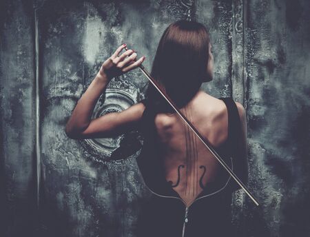 Woman in dress with violin body art holding bow