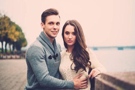 Beautiful young couple near river on autumn fogy dayの写真素材