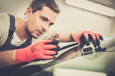 Worker on a car wash applying anti rain coating on a windshieldの写真素材