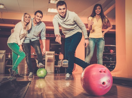 Group of four young smiling people playing bowlingの写真素材