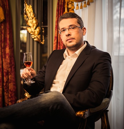 Middle-aged tasting cognac in luxury vintage style interior