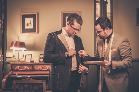 Tailor and client choosing cloth and buttons for custom made suit