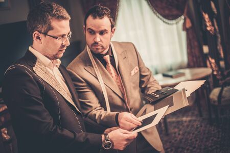 Tailor and client choosing cloth and buttons for custom made suitの写真素材