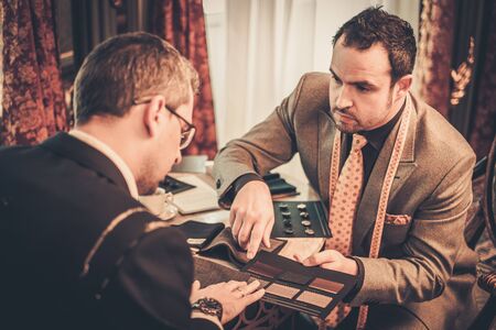 Tailor and client choosing cloth and buttons for custom made suitの写真素材
