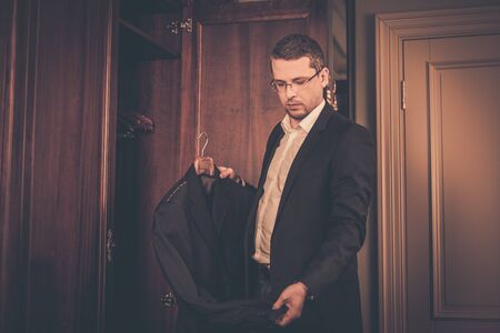 Middle-aged man taking suit from wardrobeの写真素材