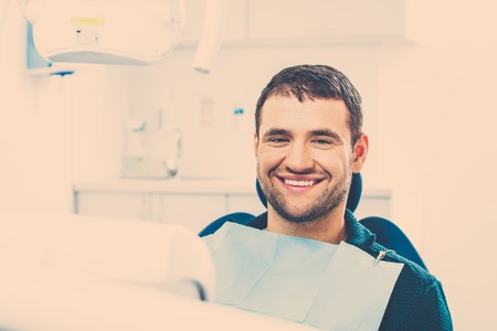 Smiling young man at dentist's surgeryの写真素材