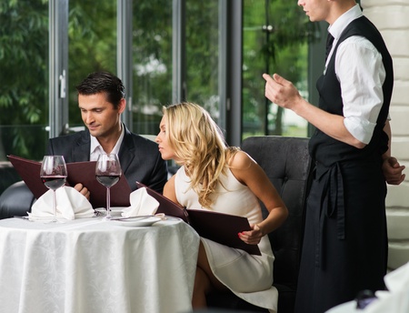 Cheerful couple with menu in a restaurant making orderの写真素材