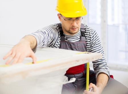 Workman measuring bathtub in new apartment interior