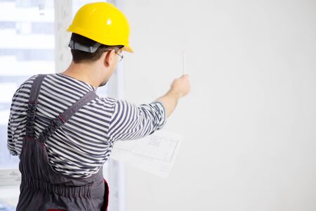 Foreman with construction plan in new building interior