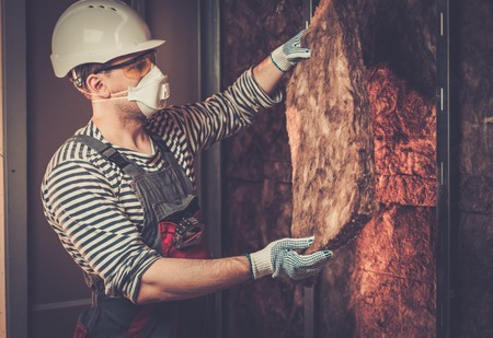 Builder in protective wear applying material on a wallの写真素材