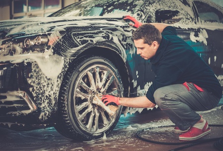 Man worker washing car's alloy wheels on a car washの写真素材
