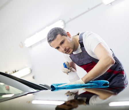 Worker on a car wash cleaning car with a spray