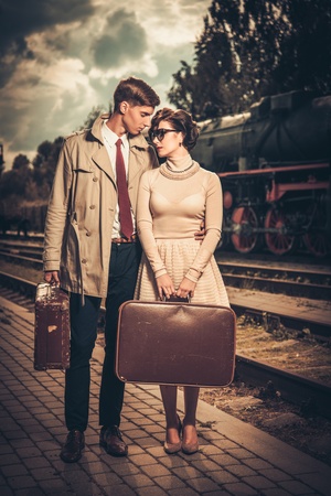 Vintage style couple with suitcases on train station platformの写真素材