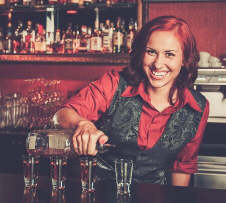 Beautiful redhead barmaid making shotsの写真素材