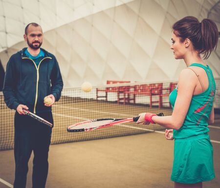 Woman player and her coach practicing on a tennis courtの写真素材