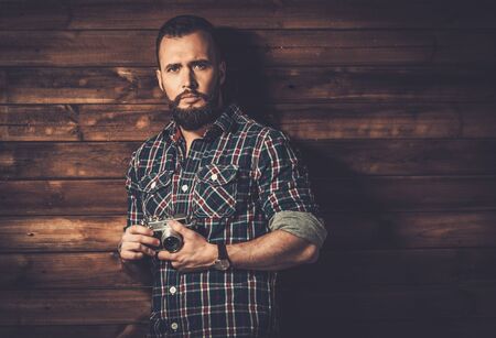 Man with beard in checkered shirt holding cameraの写真素材