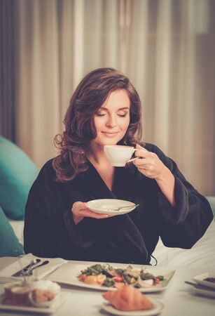 Beautiful woman having breakfast in a hotel roomの写真素材