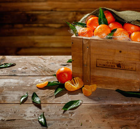 Wooden crate with tasty tangerines on a tableの写真素材