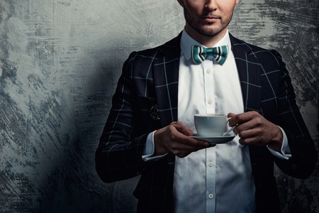 Sharp dressed fashionist with cup of coffeeの写真素材