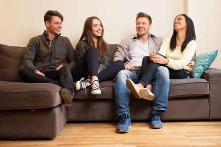 Cheerful multi-ethnic friends sitting on a sofaの写真素材