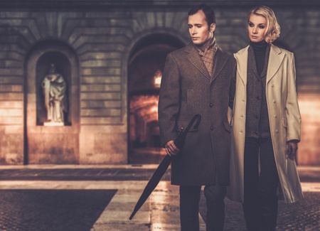Elegant couple in coats against building facade in eveningの写真素材