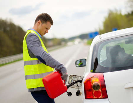 Man refuelling her car on a highway roadsideの写真素材