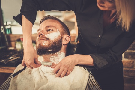 Client during beard shaving in barber shopの写真素材