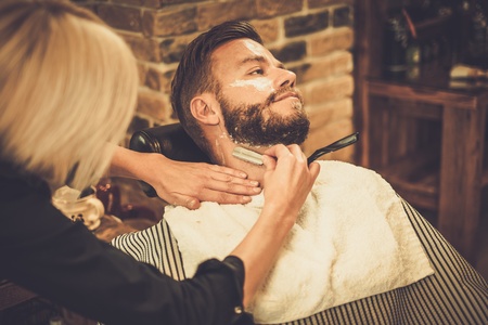 Client during beard shaving in barber shopの写真素材