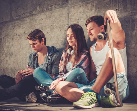 Thoughtful  friends with with skateboard and ball outdoorsの写真素材