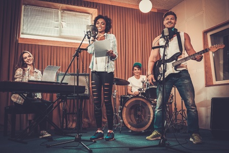 Multiracial music band performing in a recording studioの写真素材