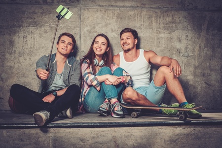 Cheerful friends with with skateboard taking selfie outdoorsの写真素材
