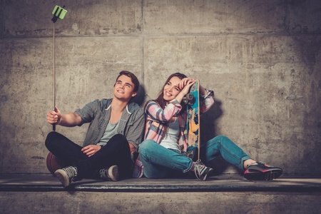 Young couple with skateboard  taking selfie outdoorsの写真素材