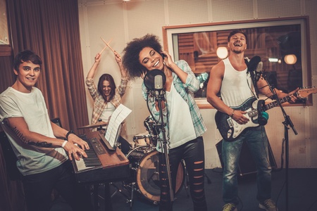 Multiracial music band performing in a recording studioの写真素材