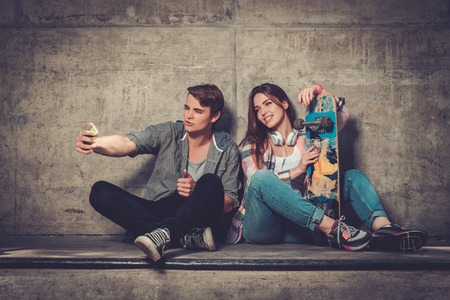 Young couple with skateboard  taking selfie outdoorsの写真素材
